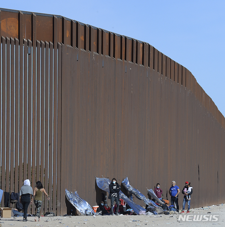 [AP/뉴시스] 멕시코와 미국 애리조나주 사이의 9m 높이 국경장벽 아래에 도착한 중미 이민들.&nbsp; 이들은 밀입국브로커들의 화물 트럭을 타고 오다가 사고를 당하기도 한다. 멕시코의 치아파스주 고속도로에서는 9일 화물트럭에 탄 이민들이 차량 전복사고로 49명이나 숨지고 37명이&nbsp; 중상을 입었다.&nbsp; 