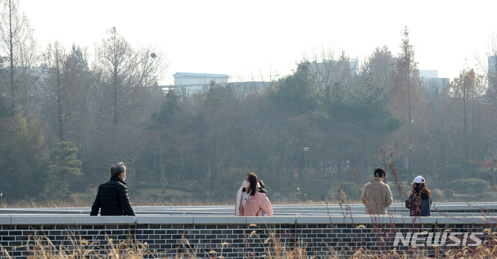 [전주=뉴시스] 김얼 기자 = 지난 7일 전주 덕진공원을 산책하는 시민들 뒤로 도심이 뿌옇게 물들어 있다. 2021.12.07. pmkeul@newsis.com