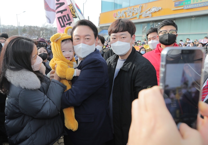 [속초=뉴시스] 전신 기자 = 윤석열 국민의힘 대선 후보가 11일 강원도 속초 대포어촌계 어업인복지회관에서 열린 강원도 살리는 현장 간담회에 참석하며 한 아이를 안고 기념촬영 하고 있다. (공동취재사진) 2021.12.11. photo@newsis.com