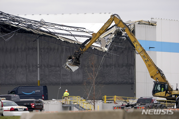 [에드워즈빌=AP/뉴시스]11일(현지시간) 인부들이 토네이도에 찢긴 미 일리노이주 에드워즈빌 소재 아마존 물류센터의 지붕을 제거하기 위해 장비를 사용하고 있다. 2021.12.12. 