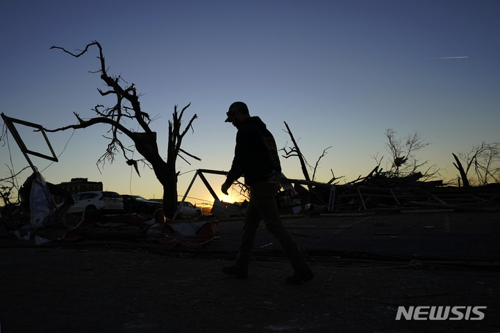 [메이필드=AP/뉴시스] 12일(현지시간) 미국 켄터키주 메이필드에서 청소부가 토네이도 여파로 훼손된 현장을 지나가고 있다. 2021.12.14.
