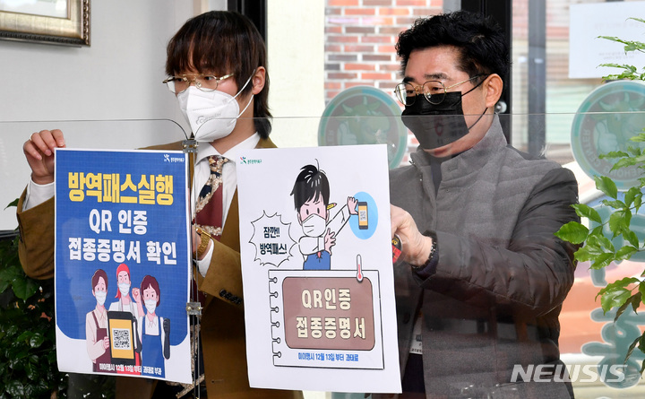 [광주=뉴시스] 변재훈 기자 = 광주 북구보건소 관계자들이 13일 광주 북구 한 음식점에서 '방역패스'(접종증명·음성확인제)' 의무화 관련 안내문을 부착하고 있다. 2021.12.13. wisdom21@newsis.com