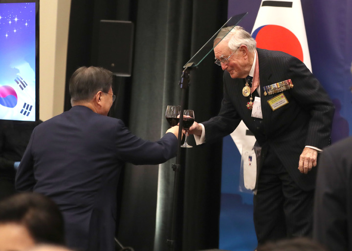 [캔버라=뉴시스] 전진환 기자 = 호주를 국빈 방문중인 문재인 대통령이 13일 호주 캔버라의 한 호텔에서 열린 한국전 참전용사 및 유가족 초청 만찬에 참석해 건배사를 한 이안 크로포드 제독과 잔을 부딪히고 있다. 2021.12.13. amin2@newsis.com