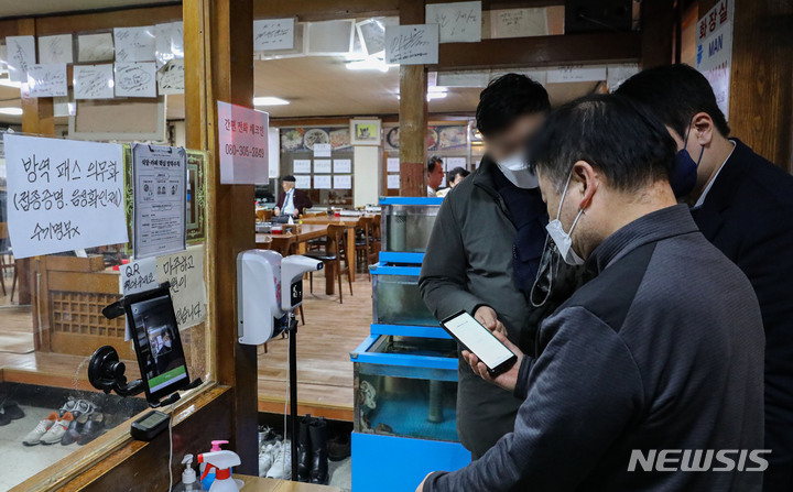 [서울=뉴시스] 권창회 기자 = 다중이용시설 방역패스 의무화가 시작된 지난 13일 밤 서울 시내 한 식당 점주가 방역패스 확인을 하고 있다. 2021.12.13. kch0523@newsis.com