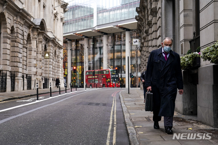 [런던(영국)=AP/뉴시스] 13일(현지시간) 영국 런던의 금융 지구에서 마스크를 쓴 시민이 텅 빈 거리를 걷고 있다. 2021.12.14.