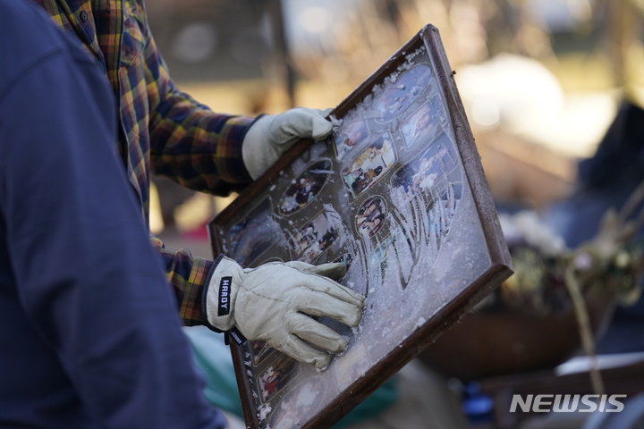 [메이필드=AP/뉴시스] 13일(현지시간) 미국 켄터키주 메이필드에서 시민이 토네이도 여파로 훼손된 집에서 찾은 가족사진을 들어보이고 있다. 2021.12.14.