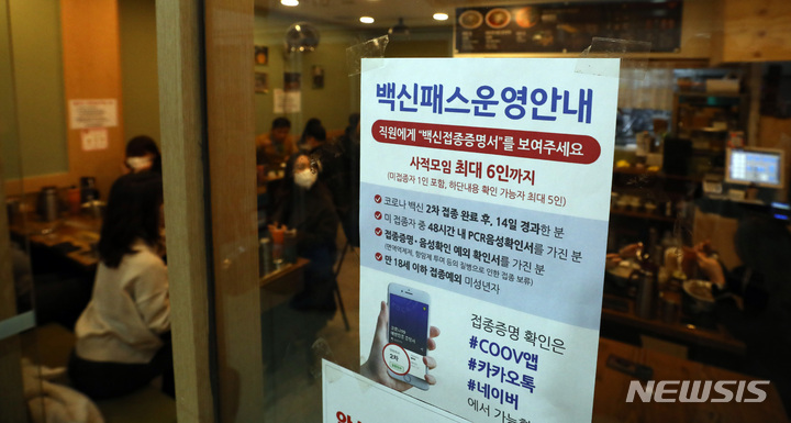 [서울=뉴시스] 이영환 기자 = 방역패스 의무화 시행 이틀째인 지난 14일 서울 시내의 한 식당에서 QR 코드 인증을 마친 시민들이 점심 식사를 하고 있다. 손영래 중앙사고수습본부(중수본) 사회전략반장은 이날 정례브리핑을 통해 "시스템 과부하 문제로 작동이 원활하지 않은 측면에서의 방역패스 미확인 사례에 대해서는 벌칙 적용을 계속 유예한다"고 밝혔다. 2021.12.14. 20hwan@newsis.com