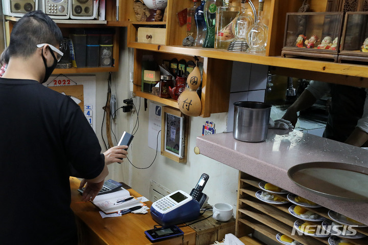 [서울=뉴시스] 백동현 기자 = 방역패스 의무화 시행 이튿날인 14일 오전 서울 시내 한 식당에서 고객들이 QR코드 인증하고 있다. 이날 방역당국은 정례브리핑을 통해 시스템 과부하 문제로 작동이 원활하지 않은 측면에서의 방역패스 미확인 사례에 대해서는 벌칙 적용을 계속 유예한다고 밝혔다. 2021.12.14. livertrent@newsis.com