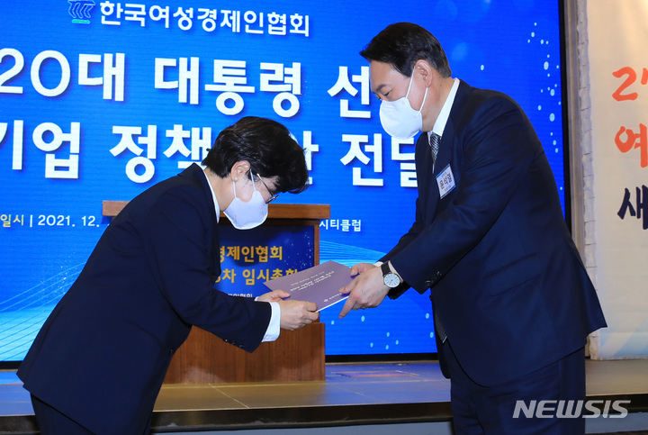 [서울=뉴시스] 국회사진기자단 = 윤석열 국민의힘 대선 후보가 14일 오후 서울 여의도 CCMM빌딩에서 열린 한국여성경제인협회 전국총회에 참석해 정윤숙 회장으로부터 여성기업 정책제안서를 전달받고 있다. 2021.12.14. photo@newsis.com