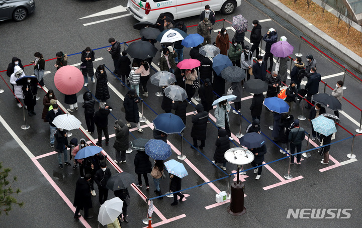 [서울=뉴시스] 추상철 기자 = 코로나19 신규 확진자수가 7850명으로 역대 최다를 기록한 15일 오전 서울 강남구보건소 선별진료소에서 우산을 쓴 시민들이 코로나19 검사를 받기 위해 길게 줄 서 있다. 2021.12.15. scchoo@newsis.com