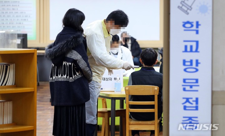 [부산=뉴시스] 하경민 기자 = 지난 16일 오후 부산 부산진구의 한 초등학교 도서관에서 '찾아가는 백신접종'을 신청한 6학년 학생들이 코로나19 백신 접종에 앞서 예진 및 대상자 확인 과정을 거치고 있다. 2021.12.31. (사진공동취재단). photo@newsis.com