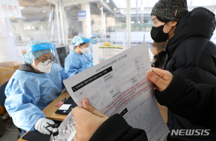[서울=뉴시스] 조수정 기자 = 18일 오전 서울 시내 한 보건소 코로나19 선별진료소에서 보건소 관계자가 질병관리청 시스템 오류로 검사자들이 수기 작성한 문진표를 확인하고 있다. 이날 오전 질병관리청에서 관리하는 코로나19 선별검사 시스템 접속에 오류가 생겨 일부 선별검사소는 조기 마감하거나 수기 접수로 운영했다. 2021.12.18. chocrystal@newsis.com