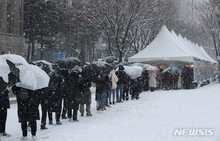 [서울=뉴시스] 조수정 기자 = 올 겨울 첫 대설주의보가 발령된 지난 18일 오후 서울시청 코로나19 임시선별검사소에서 시민들이 검사를 받기 위해 눈을 맞으며 줄서 기다리고 있다. chocrystal@newsis.com. 2021.12.19