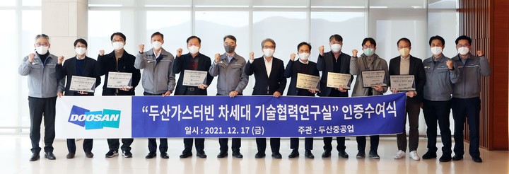 [서울=뉴시스]17일 두산중공업 창원 본사에서 열린 ‘두산가스터빈 차세대 기술협력 연구실’ 인증 수여식에서 두산중공업 박홍욱 파워서비스BG장(왼쪽 6번째), 손정락 산업부 연구개발(R&D) 전략기획단 에너지산업 MD(7번째)를 비롯해 선정된 대학 연구실 교수들이 기념 촬영을 하고 있다. (사진=두산중공업 제공) *재판매 및 DB 금지