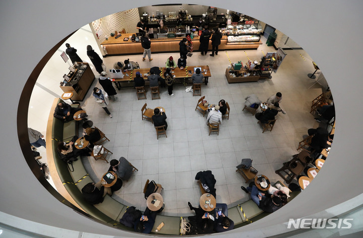 [서울=뉴시스] 권창회 기자 =사적모임 4인 제한 및 식당·카페 등의 영업시간을 오후 9시까지 제한하는 사회적 거리두기 강화 조치 시행 이튿날인 19일 오후 서울 시내 한 카페에 고객들이 4인 이하로 앉아있다. 2021.12.19. kch0523@newsis.com