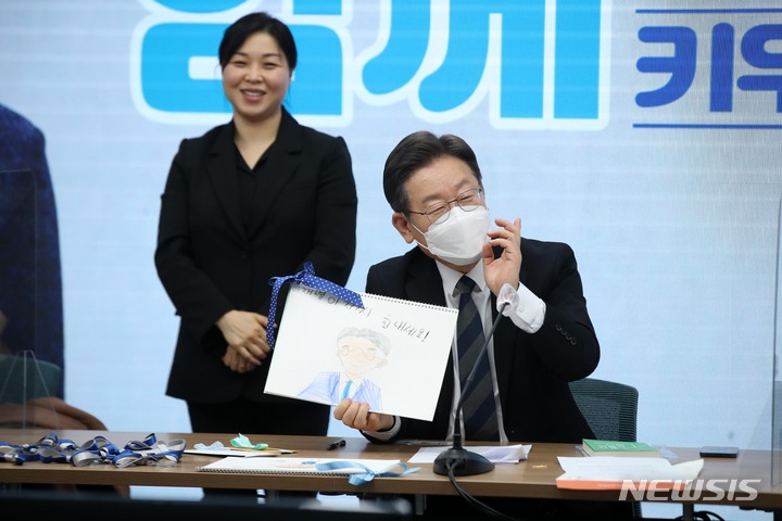 [서울=뉴시스] 김선웅 기자 = 이재명 더불어민주당 대선 후보가 20일 서울 여의도 더불어민주당 중앙당사에서 열린 '국가가 함께 키우겠습니다' 전국민 선대위 회의에서 참석자 자녀로부터 받은 선물을 들어보이고 있다. 2021.12.20 mangusta@newsis.com