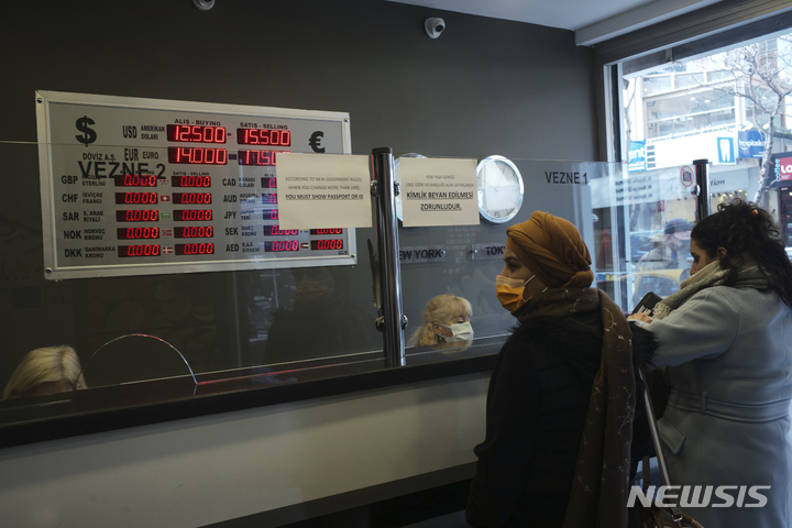 [앙카라(터키)=AP/뉴시스]지난해 12월21일 터키 수도 앙카라의 한 환전소에서 사람들이 환율을 적어 놓은 전관팡을 보고 있다. 지난 12월 터키의 연간 인플레이션이 36.08%로 뛰어올라 19년 만에 가장 빠른 속도로 상승한 것으로 3일 발표된 공식 통계에서 나타났다. 2022.1.3