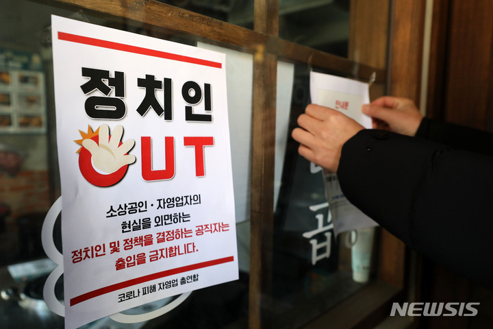 [서울=뉴시스] 백동현 기자 = 정부 방역지침에 반발한 자영업자단체 총궐기가 예고된 22일 오후 서울 시내 한 먹자골목에서 코로나피해자영업총연합(코자총) 회원들이 '정치인 출입 금지' 및 '간판 소등 항의 예고' 스티커를 붙이고 있다. 2021.12.22. livertrent@newsis.com