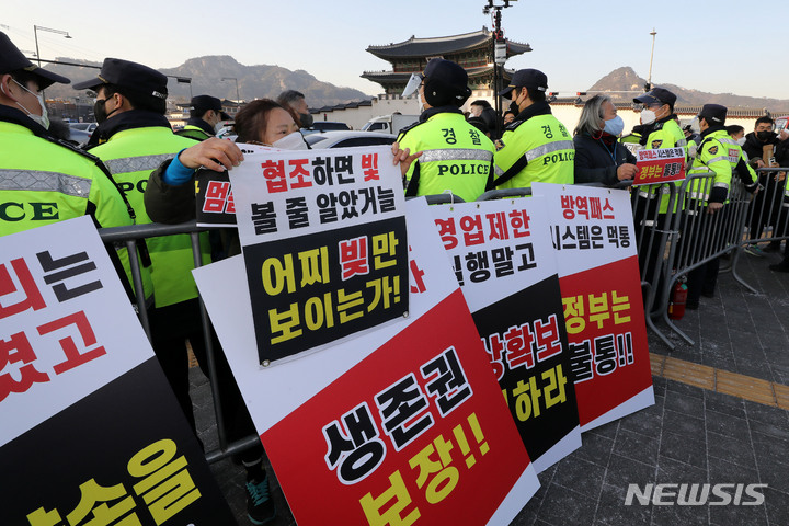 [서울=뉴시스] 백동현 기자 = 22일 오후 서울 종로구 광화문 앞에서 정부 방역지침에 반발한 자영업자단체 총궐기가 열린 가운데 집회 인원 제한으로 인해 들어가지 못한 참석자가 펜스 밖에서 구호를 외치고 있다. 2021.12.22. livertrent@newsis.com