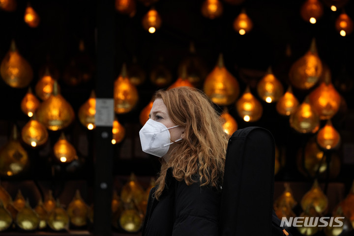 [런던=AP/뉴시스]영국 런던에서 마스크를 쓴 시민이 크리스마스 장식 앞을 지나가고 있다. 2021.12.22.