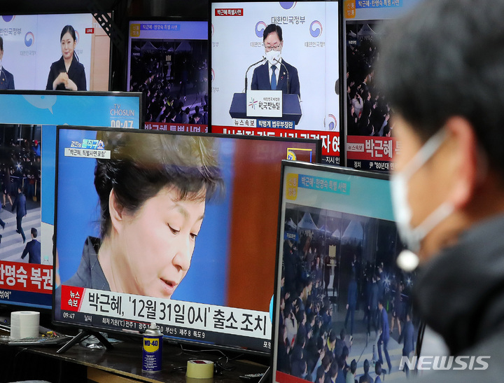 [서울=뉴시스] 백동현 기자 = 정부가 박근혜 전 대통령 특별사면을 발표한 24일 오전 서울 중구 황학동 시장에서 한 시민이 관련 뉴스를 시청하고 있다. 2021.12.24. livertrent@newsis.com