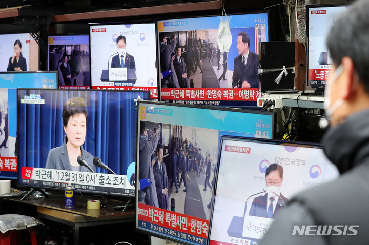[서울=뉴시스] 백동현 기자 = 정부가 박근혜 전 대통령 특별사면을 발표한 24일 오전 서울 중구 황학동 시장에서 한 시민이 관련 뉴스를 시청하고 있다. 2021.12.24. livertrent@newsis.com
