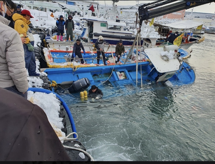 [강릉=뉴시스] 김경목 기자 = 많은 눈이 내린 25일 어업인들과 해양경찰관이 강원도 강릉시 주문진읍 주문진항에서 눈 무게를 이기지 못하고 물에 반쯤 잠긴 어선이 침몰하지 않도록 작업을 하고 있다. (사진=속초해양경찰서 제공) 2021.12.25. photo@newsis.com *재판매 및 DB 금지