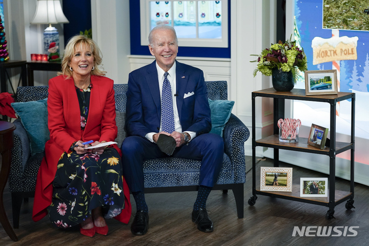 [워싱턴=AP/뉴시스]조 바이든(오른쪽) 미국 대통령과 영부인 질 바이든 여사가 24일(현지시간) 아이들에게 산타클로스의 행방을 추적해 알려주는 북미항공우주사령부(NORAD)와의 화상 행사에 참여 중이다. 2021.12.25.photo@newsis.com