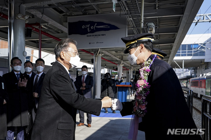 [울산=뉴시스] 김진아 기자 = 문재인 대통령이 28일 울산 태화강역에서 열린 동남권 4개 철도건설사업 개통식에서 구봉진 부기관사에게 꽃목걸이를 걸어주고 있다. 2021.12.28. bluesoda@newsis.com