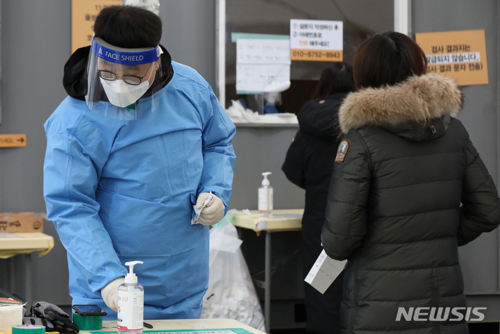 [서울=뉴시스] 조수정 기자 = 전국에 한파 특보가 발효된 지난해 12월27일 서울 서대문구 신촌기차역 공영주차장 코로나19 임시선별검사소에서 현장 직원이 핫팩을 손에 쥐며 손을 녹이고 있다. 2022.01.01. chocrystal@newsis.com