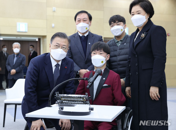 [공주=뉴시스] 김진아 기자 = 문재인 대통령과 김정숙 여사가 29일 충남 공주시 공주대학교 옥룡캠퍼스에서 열린 공주대학교 부설 특수학교 설립 간담회를 마친 뒤 표형민 맑은소리 하모니카 앙상블 단원 등과 기념촬영을 하고 있다. 2021.12.29. bluesoda@newsis.com