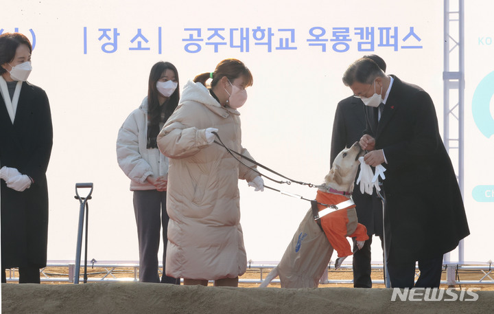 [공주=뉴시스] 김진아 기자 = 문재인 대통령이 29일 충남 공주시 공주대학교 옥룡캠퍼스에서 열린 공주대학교 부설 특수학교 설립 기공식에서 박솔이 공주대 특수교육과 학생의 안내견 '평화'가 반가움을 표시하자 인사를 하고 있다. 2021.12.29. bluesoda@newsis.com