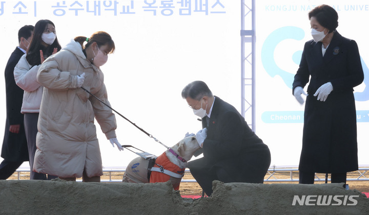 [공주=뉴시스] 김진아 기자 = 문재인 대통령이 29일 충남 공주시 공주대학교 옥룡캠퍼스에서 열린 공주대학교 부설 특수학교 설립 기공식에서 박솔이 공주대 특수교육과 학생의 안내견 '평화'가 반가움을 표시하자 인사를 하고 있다. 2021.12.29. bluesoda@newsis.com