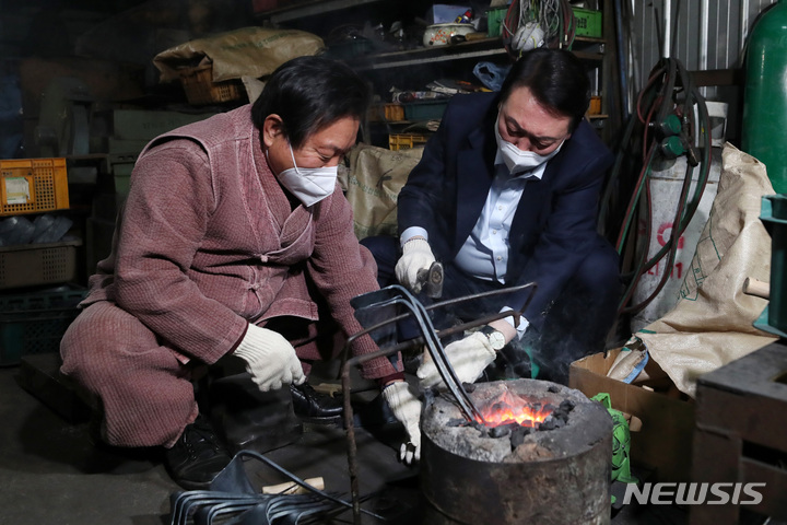 [영주=뉴시스] 전신 기자 = 윤석열 국민의힘 대선후보가 30일 경북 영주시 영주대장간을 방문, 직접 만든 호미를 글로벌 전자상거래 업체인 아마존을 통해 판매하며 인기를 끈 'K-호미'의 주인공 석노기씨와 대화하며 호미 제작 체험을 하고 있다. (공동취재사진) 2021.12.30. photo@newsis.com