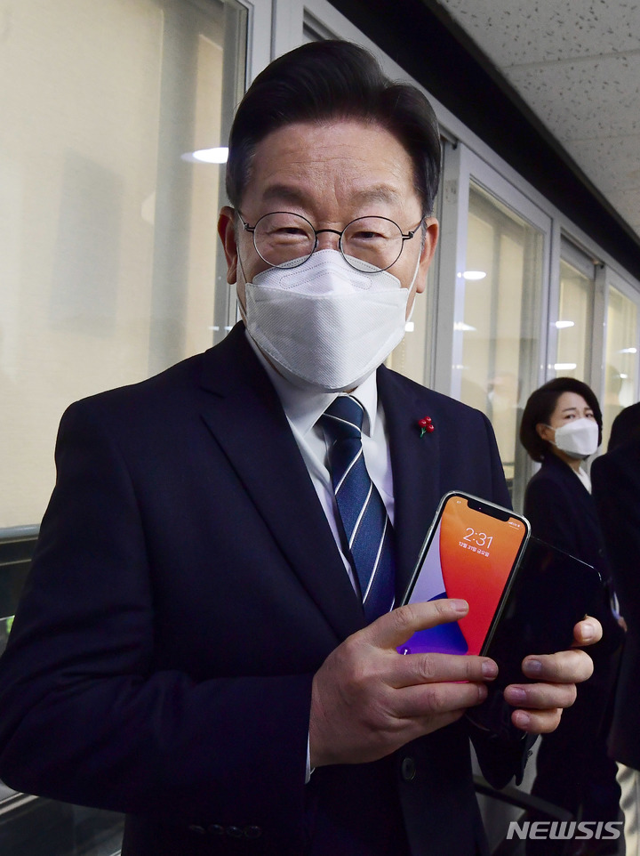 [서울=뉴시스] 김선웅 기자 = 이재명 더불어민주당 대선 후보가 31일 오후 서울 여의도 더불어민주당 중앙당사에서 소확행 국민공모 캠페인 기자회견을 마치고 전달받은 국민제안 시스템 '이재명 플러스' 전용 스마트폰을 들고 있다. (공동취재사진) 2021.12.31. photo@newsis.com