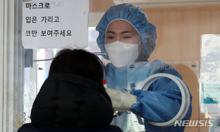 [서울=뉴시스] 이영환 기자 = 임인년 (壬寅年) 새해 첫날인 1일 오전 서울 중구 서울역광장에 마련된 코로나19 임시선별검사소에서 한 의료진이 검체를 채취하고 있다. 2022.01.01. 20hwan@newsis.com