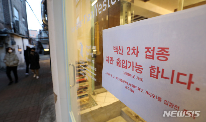 [서울=뉴시스] 고범준 기자 = 코로나19 확산세를 차단하기 위한 방역패스(접종증명·음성확인제)가 시행중인 지난 4일 오후 서울 종로구 대학로 한 카페에 백신접종 출입 관련 안내문이 붙어 있다. 2022.01.04. bjko@newsis.com