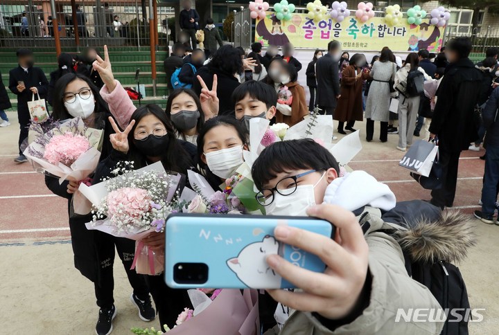 [부산=뉴시스] 하경민 기자 = 지난 5일 오전 부산 해운대구 센텀초등학교 운동장에서 졸업식을 마친 졸업생들이 기념사진을 찍고 있다. 학급당 학생 38명으로 과밀학교인 이 학교는 교실 증축공사를 위해 1개월 정도 앞당겨 졸업식을 열었다. 2022.01.24. yulnetphoto@newsis.com