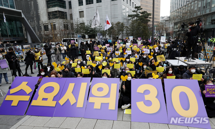[서울=뉴시스] 조성우 기자 = 5일 오후 서울 종로구 옛 주한일본대사관 인근에서 열린 '수요시위 30주년 기념 일본군성노예제 문제해결을 위한 1525차 정기 수요시위'에서 참석자들이 30주년 기념 피켓을 흔들고 있다. 2022.01.05. xconfind@newsis.com
