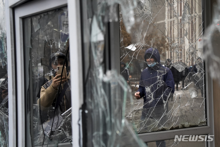 [알마티=AP/뉴시스] 지난 5일(현지시간) 카자흐스탄 알마티에서 한 남성이 반정부 시위대에 의해 파손된 유리창을 찍고 있다. 2022.01.07.