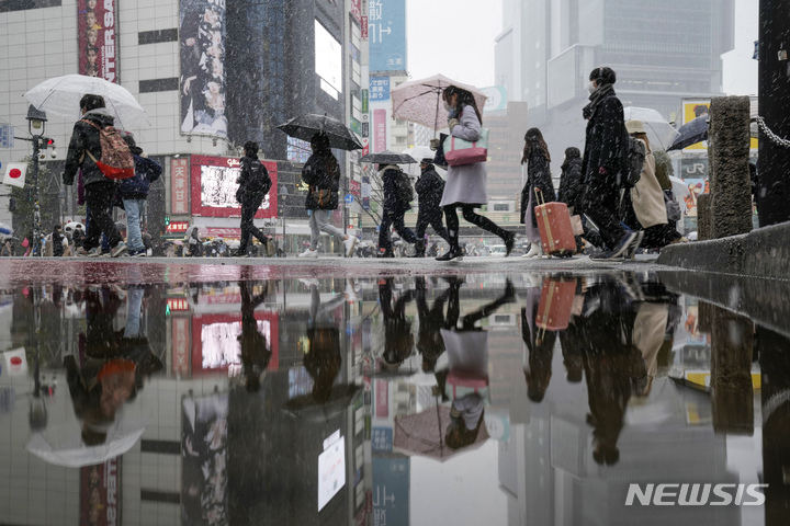 [도쿄(일본)=AP/뉴시스]지난 6일 눈이 내리는 일본 도쿄 시부야의 거리를 시민들이 우산을 쓰고 건너고 있다. 2022.01.07.