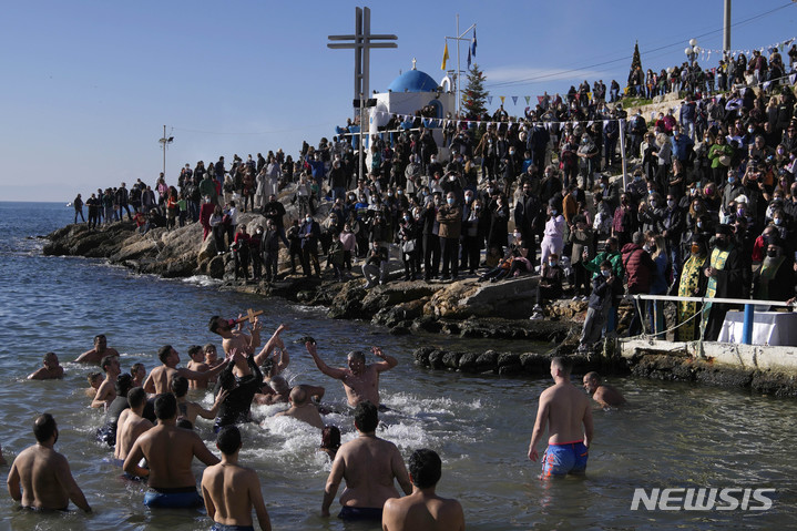 [피레아스(그리스)=AP/뉴시스] 아테네에서 가까운 그리스 남부의 관광지 피레아스 항구에서 올해 6월 6일 순례자들이 세례식을 하고 있다.&nbsp; 공식 행사는 코로나19 오미크론 변이 바이러스의 확산으로 인해 취소되었다.&nbsp; 