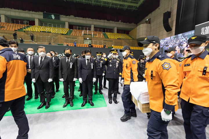 [평택=뉴시스] 8일 오전 평택 이충문화체육센터에서 경기도청장으로 마련된 故 이형석 소방경(50), 故 박수동 소방장(31), 故 조우찬 소방교(25)의 합동 영결식에서 문재인 대통령과 오병권 경기도지사 권한대행(장의위원회 위원장) 등 참석자들이 운구행렬을 향해 조의를 표하고 있다. (사진=경기도 제공) 2022.01.08. photo@newsis.com *재판매 및 DB 금지