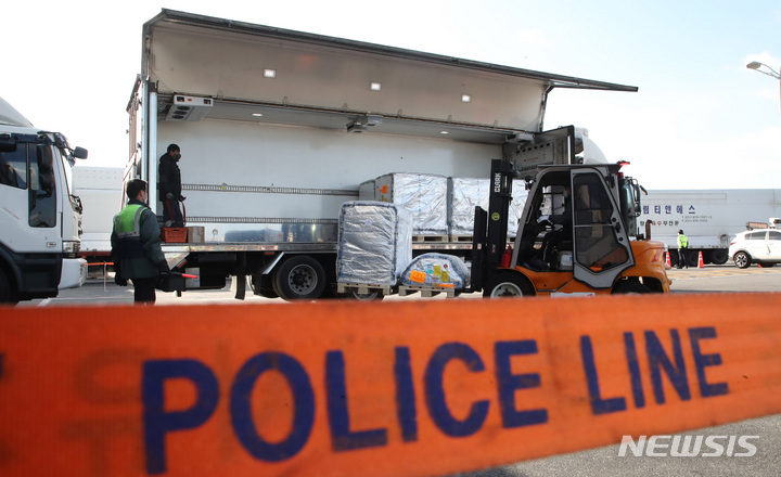 [인천공항=뉴시스] 공항사진기자단 = 13일 오후 인천국제공항 화물터미널에서 관계자들이 화이자사의 경구용(먹는) 코로나19 치료제 팍스로비드 2만1000명분을 수송차량에 옮겨 싣고 있다. 2022.01.13. photo@newsis.com