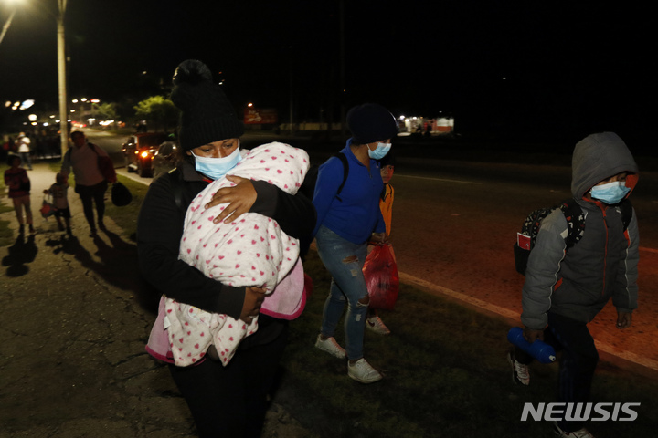 [산페드로 술라( 온두라스)= AP/뉴시스] 온두라스의 한 버스정류장에 집결한 미국이민행 캐러밴 600여명 가운데 아기를 안은 이민이 15일 (현지시간) 어두운 새벽길을 나서고 있다.&nbsp; 