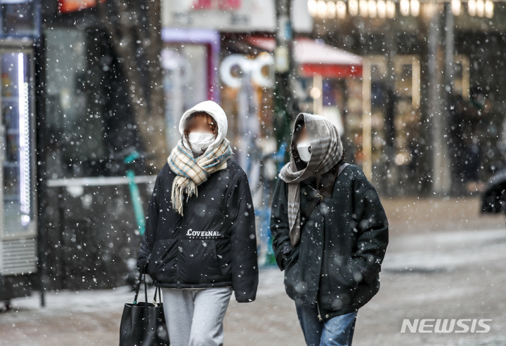 [서울=뉴시스] 정병혁 기자 = 지난 17일 오후 서울 중구 명동거리를 찾은 시민들이 내리는 눈을 맞으며 이동하고 있다. 2022.01.17. jhope@newsis.com