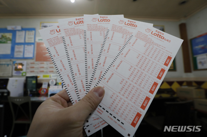 [서울=뉴시스] 고승민 기자 = 지난해 6조원에 육박하는 복권이 팔리면서 역대 최고액을 갈아치웠다. 성인 10명 중 6명은 1년에 한 번 이상 복권을 구매한 경험이 있을 정도로 판매액은 매년 증가 추세다. 기획재정부 복권위원회는 지난해 복권 판매액은 전년(5조4152억원) 대비 10.3% 증가한 5조9755억원으로 잠정 집계됐다고 18일 밝혔다. 코로나19 사태가 장기화되면서 경기가 침체되고, 경마나 경륜 등 다른 사행산업이 위축된 탓에 복권 판매가 늘어난 것으로 분석된다. 사진은 이날 서울의 한 복권판매점 모습. 2022.01.19. kkssmm99@newsis.com