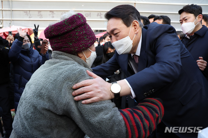 [대전=뉴시스] 전신 기자 = 윤석열 국민의힘 대선 후보가 21일 대전 동구 중앙시장을 방문해 한 상인에게 마늘을 구입한 후 포옹하고 있다. 2022.01.21. photo1006@newsis.com