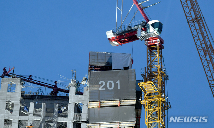 [광주=뉴시스] 류형근 기자 = 광주 서구 화정동 현대산업개발 신축 아파트 붕괴 사고 11일째인 21일 오후 구조당국 등이 사고 아파트 벽에 설치돼 있는 크레인 철거작업을 하고 있다. 사고 현장에 운적석이 남아있다. 2022.01.21. hgryu77@newsis.com