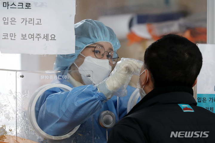 [서울=뉴시스] 백동현 기자 = 오미크론 변이 확산세가 여전한 가운데 코로나19 신규 확진자가 7,630명으로 집계된 23일 오전 서울 중구 서울역광장 임시선별검사소에서 의료진이 검체를 채취하고 있다. 2022.01.23. livertrent@newsis.com